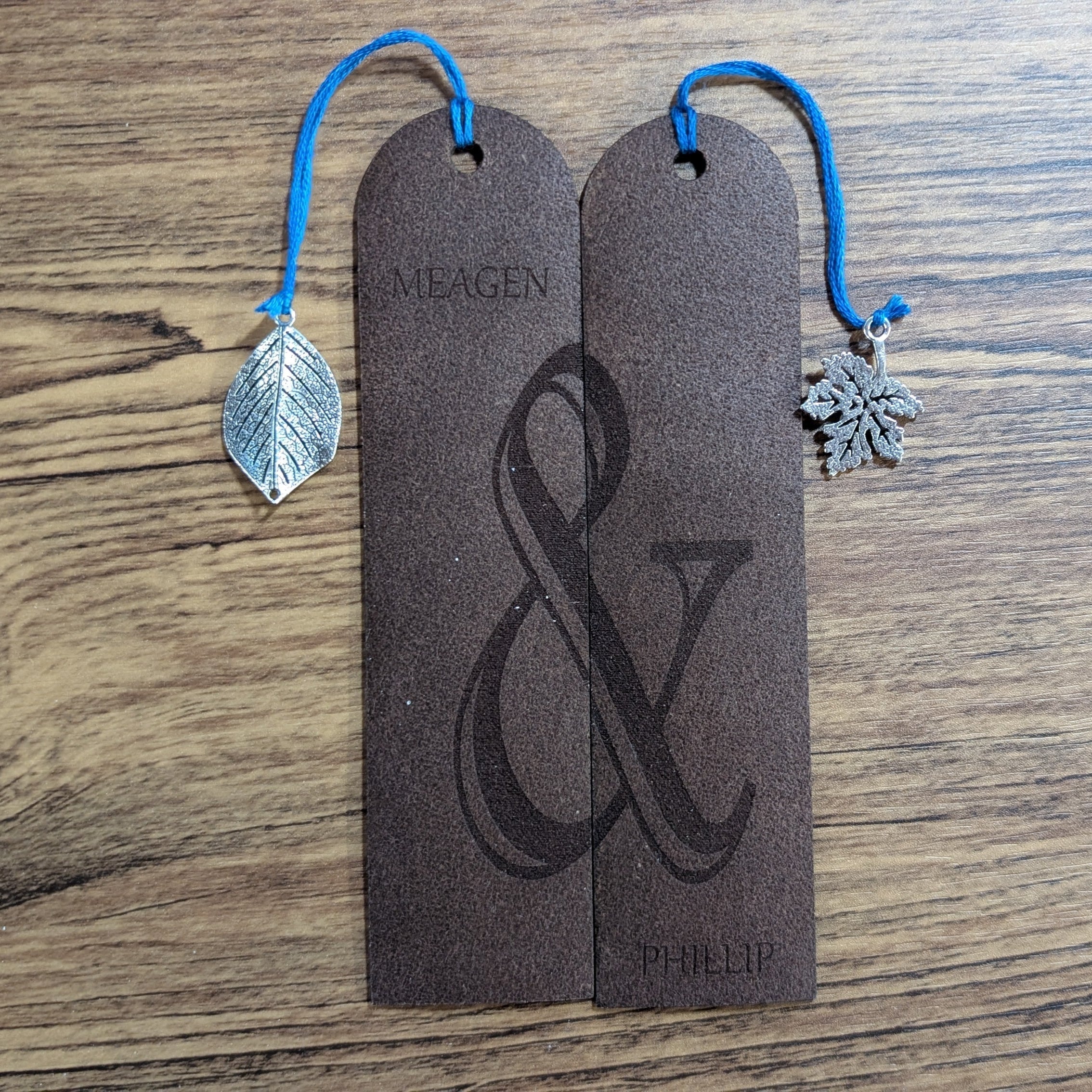 Couples leather bookmark set side by side, engraved with two names and a shared ampersand